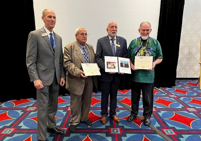 R10 DSM Award Ceremony at the Global Reception of the ASCE 2022 Convention. Pictured are 4 people standing in front of a screen, holding awards and smiling at the camera. 