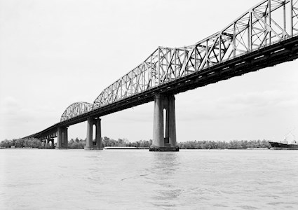 Photo shows a steel bridge with concrete piers. The bridge spans a river. 