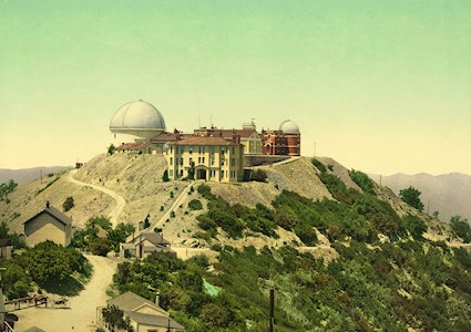 Image shows a rooftop facility consisting of a multistory building, two domed structures, and housing. A road leads to the top of the mountain. 