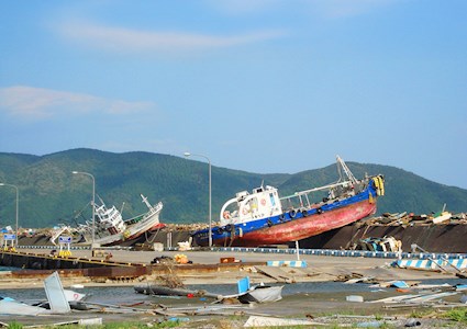 A tsunami caused a ferry to land on a pier. The pier is strewn with other debris as well.