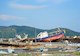 A tsunami caused a ferry to land on a pier. The pier is strewn with other debris as well.