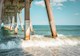 The ocean splashes around concrete piers.