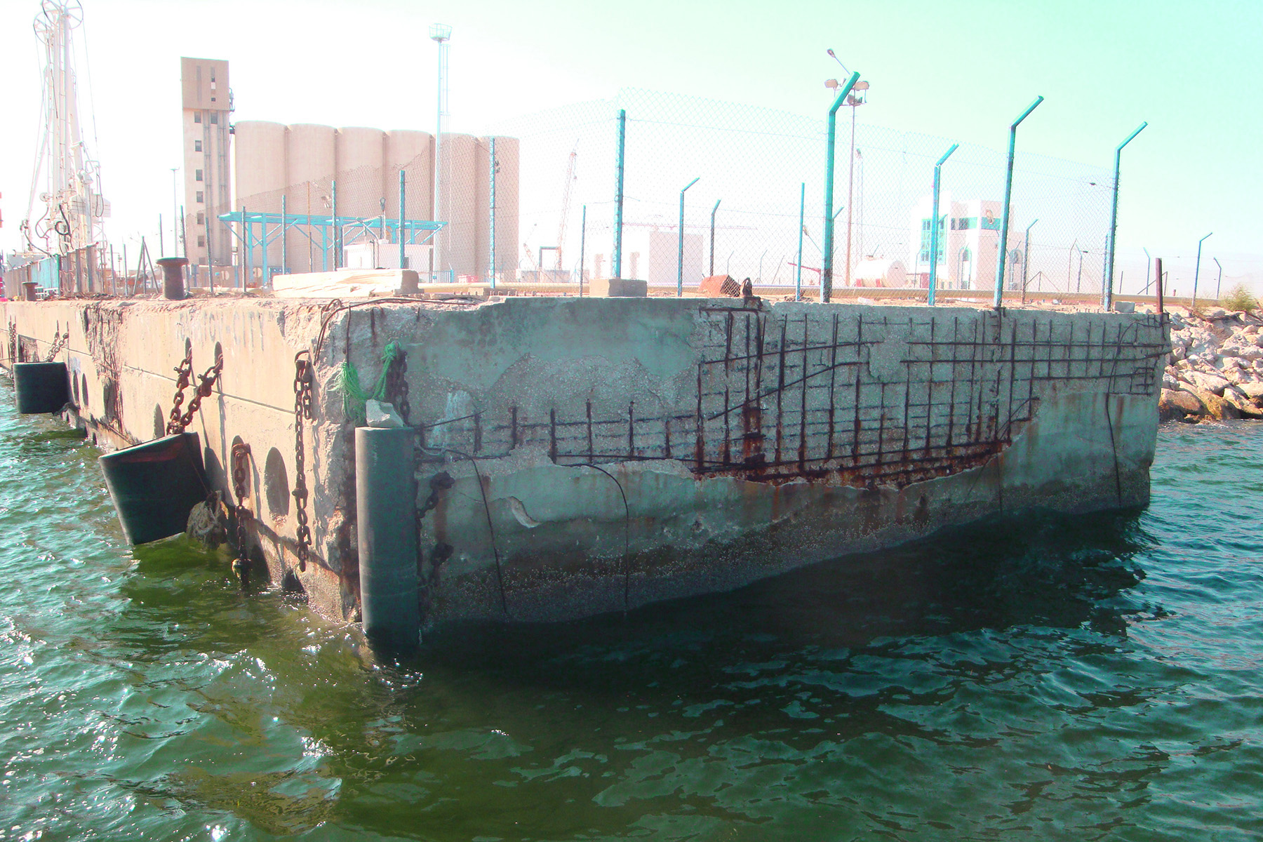 Photograph shows a precast-concrete pier showing significant open corrosion and spall damage.