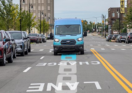 blue van drives along a street