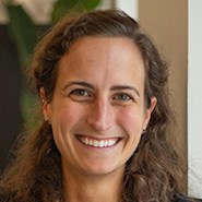 Woman with curly brown hair smiles at the camera.